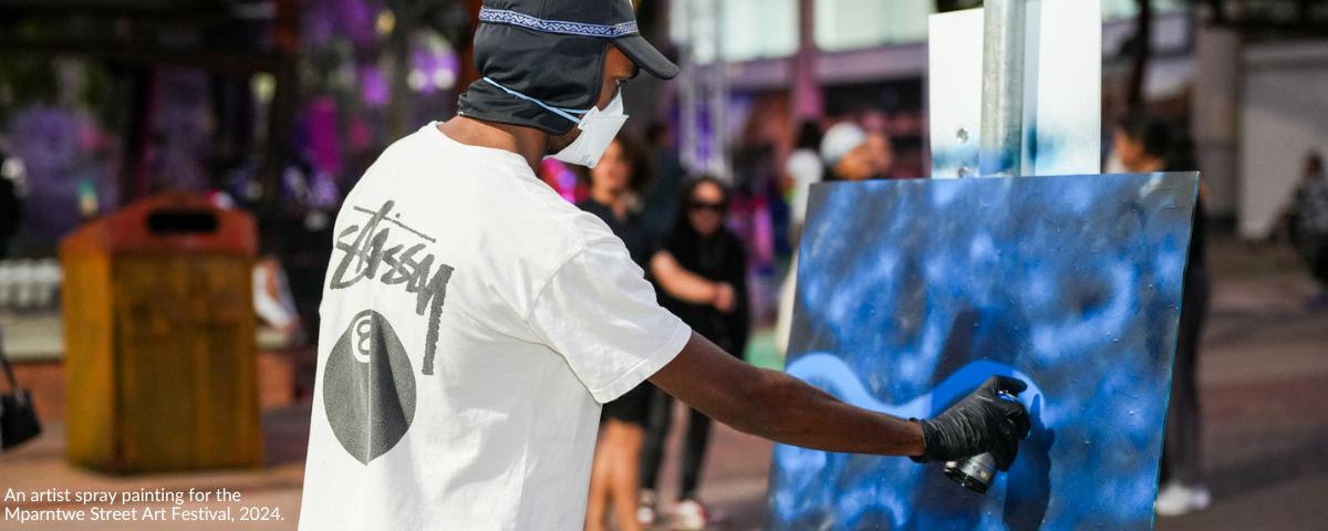 An artist spray painting for the Mparntwe Street Art Festival, 2024.