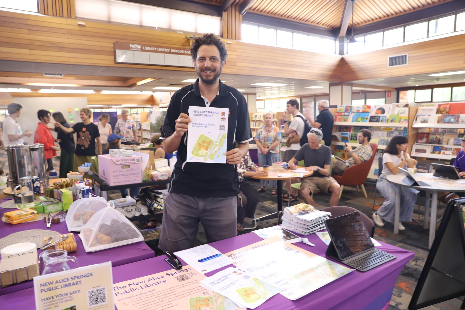 Jordan, the Library Manager, holding up a printed version of the survey created during Phase 1 of the New Library Consultation.